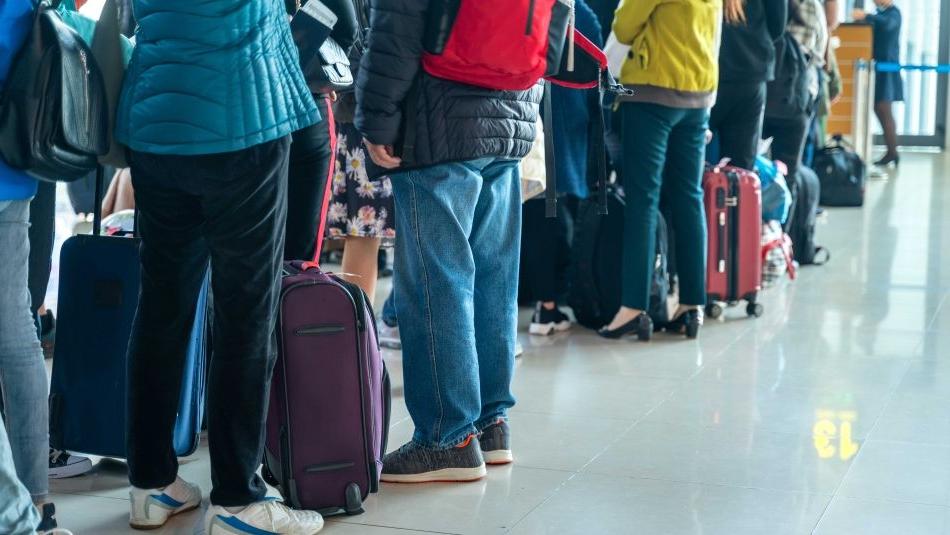 人们在机场办理登机手续时拿着行李排队.