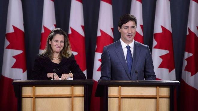 “贾斯汀·特鲁多和克里斯蒂亚·弗里兰站在加拿大国旗前的讲台上”